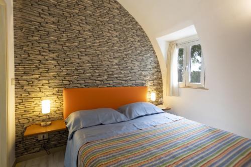 a bed in a bedroom with a brick wall at 3 Sirene Sciacca Fronte Mare in Sciacca