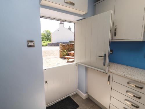 a kitchen with white cabinets and a door with a window at Rose Cottage in Settle