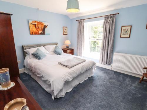 a bedroom with a bed with blue walls and a window at Rose Cottage in Settle