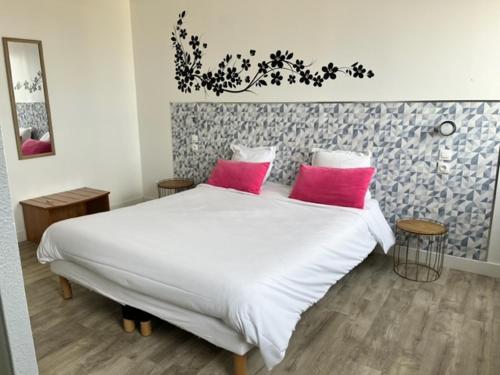 una camera con un letto bianco con due cuscini rosa di Hôtel Résidence du Golf a Calais