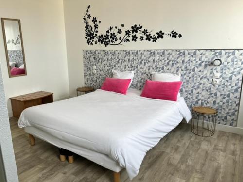 a bedroom with a white bed with two pink pillows at Hôtel Résidence du Golf in Calais