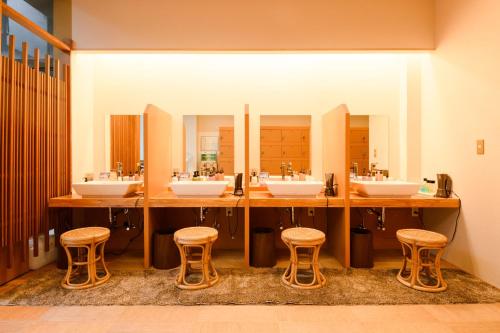a bathroom with four sinks and three stools at Shirasagiyu Tawaraya in Kaga