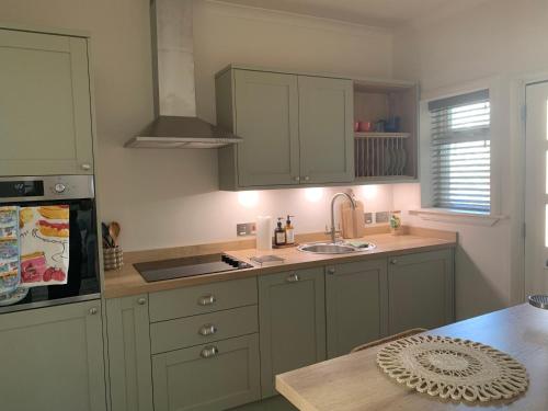 a kitchen with green cabinets and a sink and a table at Harbour quay in Wick