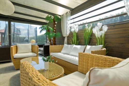 a balcony with wicker chairs and a couch and tables at Pokoje Gościnne IDALIA - Blisko Plaży Komfort i Wygoda in Karwia