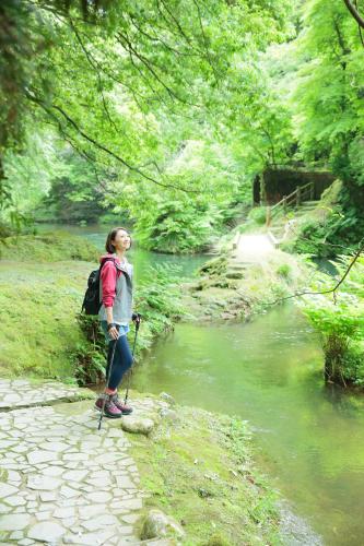 a woman is standing next to a river at Shirasagiyu Tawaraya in Kaga