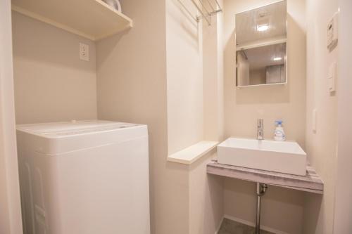een kleine badkamer met een wastafel en een wasmachine bij Your best choice for travel in Yoyogi EoY6 in Tokyo