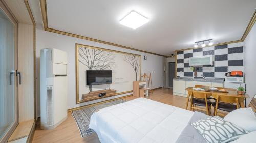 a bedroom with a white bed and a kitchen at Maremonte Pension in Geoje 