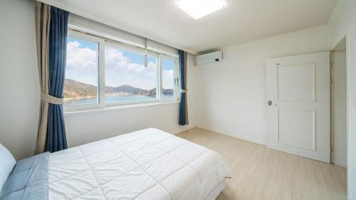 a bedroom with a bed and a large window at Maremonte Pension in Geoje 