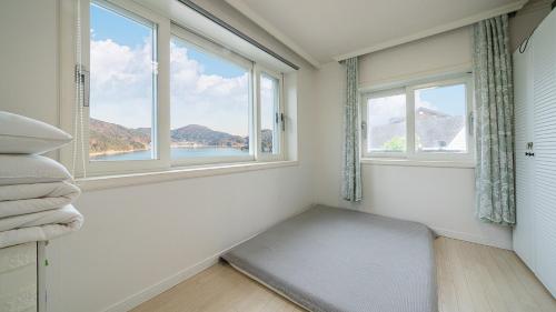 a room with two windows and a bed with a window seat at Maremonte Pension in Geoje 