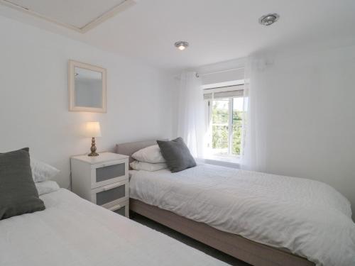 Duas camas num quarto branco com uma janela em White Horse Cottage em Weymouth