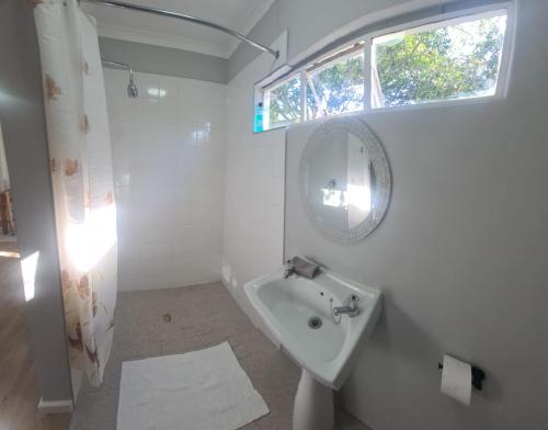 a white bathroom with a sink and a mirror at Cottage on Ilchester in Grahamstown