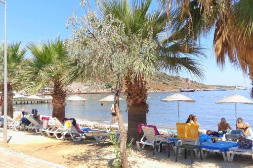 a group of people sitting on a beach with chairs and umbrellas at MAGNIFICENT VIEW with Private Pool & Piano, 3 Bedroom Villa, MIN 4 nigths in Gundogan