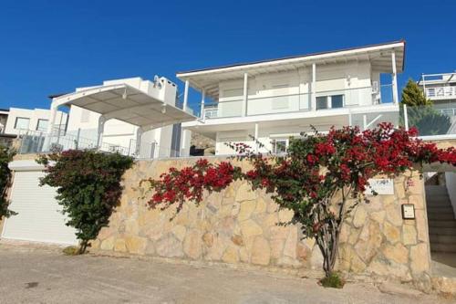 a house with red flowers on a stone wall at MAGNIFICENT VIEW with Private Pool & Piano, 3 Bedroom Villa, MIN 4 nigths in Gundogan