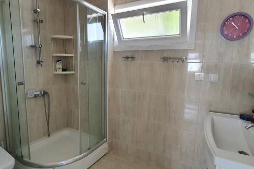 uma casa de banho com chuveiro e um relógio na parede em MAGNIFICENT VIEW with Private Pool & Piano, 3 Bedroom Villa, MIN 4 nigths em Gundogan