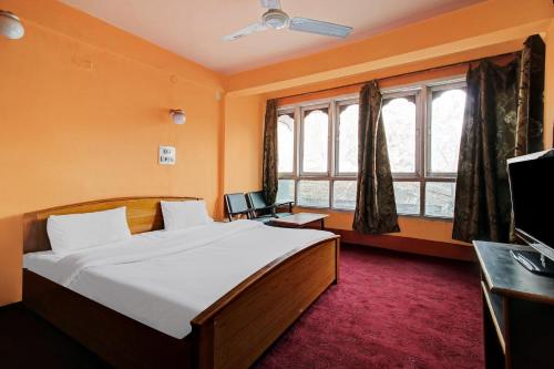 a bedroom with a bed and a desk and windows at Hotel Royal inn and restaurant in Srinagar