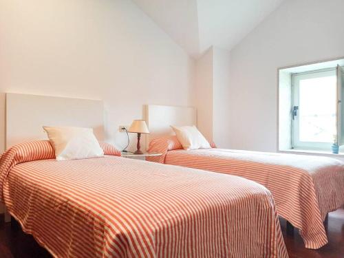 duas camas com lençóis listrados num quarto branco em Apartamento calle Real em Cambados
