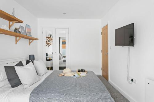 a white bedroom with a bed and a flat screen tv at Plover 1, The Cove - On site pool - Wi-Fi in Brixham