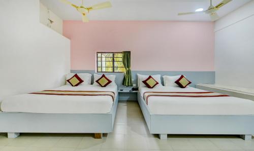 two beds in a room with white walls and a window at MADRASl AIRPORT HOTEL - NEAR AlRPORT in Chennai