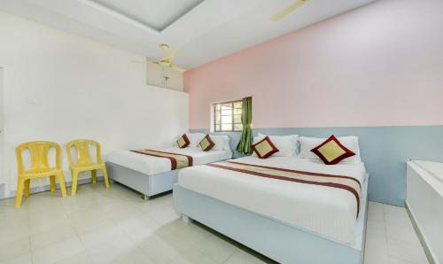 a bedroom with two beds and a table and chairs at MADRASl AIRPORT HOTEL - NEAR AlRPORT in Chennai