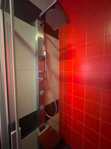 czerwona łazienka z prysznicem i czerwoną ścianą wyłożoną kafelkami w obiekcie Pina Colada - Neptun Park by OneApartments w Gdańsku