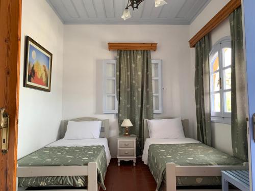 two beds in a room with two windows at Patmos Maria Studios in Skala