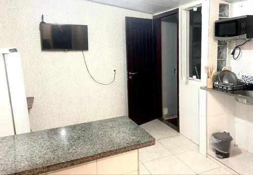 uma cozinha com um balcão e uma televisão na parede em Casa top aeroporto em Macaé