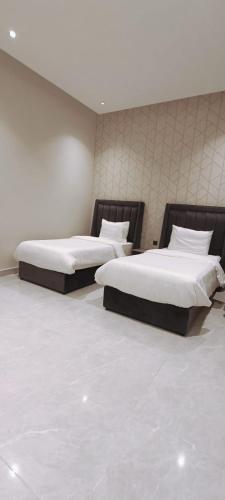 two beds in a room with white sheets and pillows at شاليهات أبيات الفندقية in Al Baha