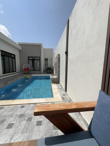 een zwembad met een bank naast een gebouw bij شاليهات أبيات الفندقية in Al Baha