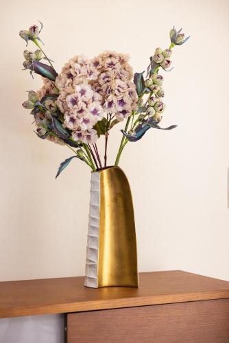 a gold vase with flowers on a table at Niovi Luxury Apartment in Samos