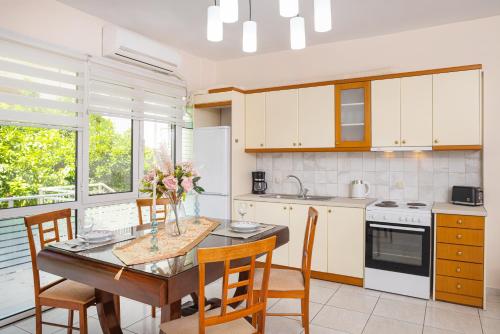 una cucina con tavolo e sedie in legno e una cucina con armadietti bianchi di Niovi Luxury Apartment a Samos