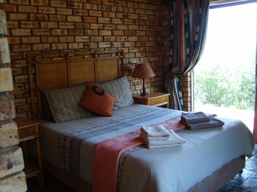 Ce lit se trouve dans une chambre dotée d'un mur en briques. dans l'établissement Thirsty Falls Guest Farm, à Maanhaarrand