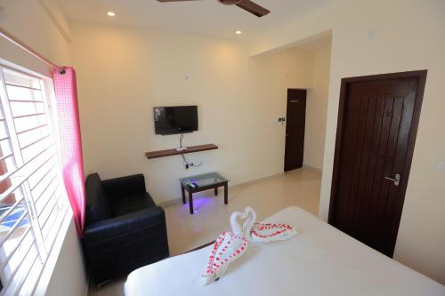 ein Wohnzimmer mit einem Tisch, einem Sofa und einem TV in der Unterkunft Thiru Pavilion Retreat in Mahabalipuram