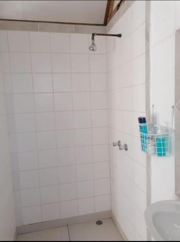 y baño de azulejos blancos con lavabo y ducha. en Hoenerhok en Vanrhynsdorp