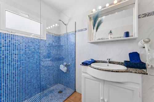 y baño de azulejos azules con lavabo y ducha. en Home2Book Charming Apt Caleta de Caballo Beach, en Caleta de Caballo