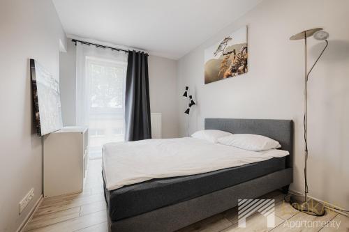 a bedroom with a bed with white sheets and a window at Primo V by LookAp in Łódź
