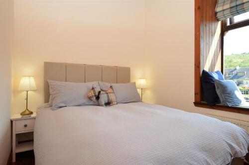 a bedroom with a white bed with a window at Cairnbaan House in Cairnbaan