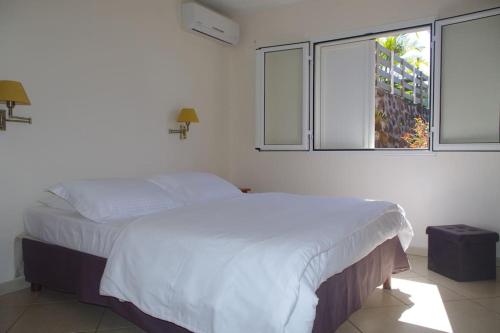 ein Schlafzimmer mit einem weißen Bett und einem Fenster in der Unterkunft LE BIGARADIER in Sainte-Rose