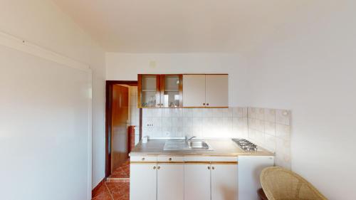 una cucina con armadi bianchi e lavandino di Jaska & Jelica House apartments a Metajna