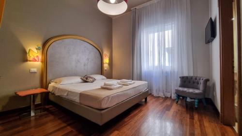 a bedroom with a large bed and a chair at Locanda Al Volo Tommaseo in Trieste