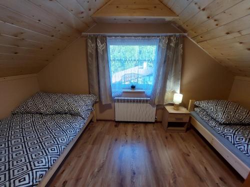 維斯瓦的住宿－Domek pod soszowem，阁楼卧室设有两张床和窗户。