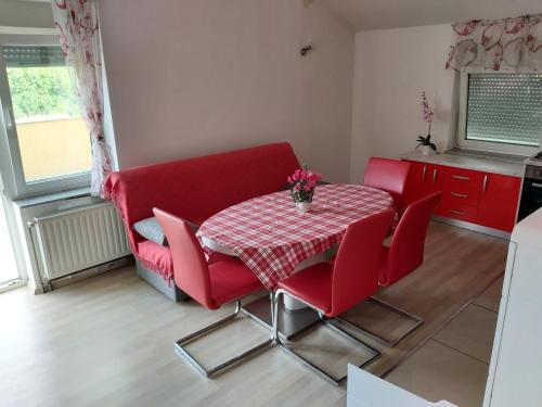 a red dining room table with red chairs and a red couch at APARTMENTS KRAPEC3 in Ježdovec