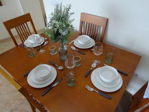 a wooden table with plates and wine glasses on it at Apartamento La Fuente Alcaucin in Alcaucín