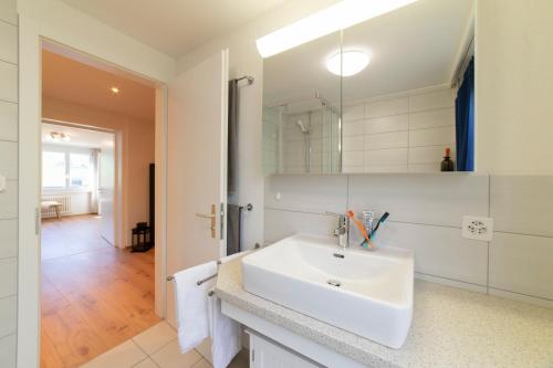 ein weißes Badezimmer mit einem Waschbecken und einem Spiegel in der Unterkunft Lisighaus in Wildhaus