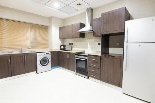 a kitchen with wooden cabinets and a white refrigerator at Better Living Apartment in Dubai