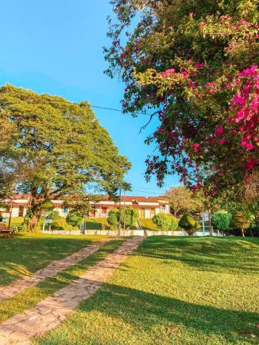 a path in a park with trees and pink flowers at Hotel Pontal de Tiradentes in Tiradentes