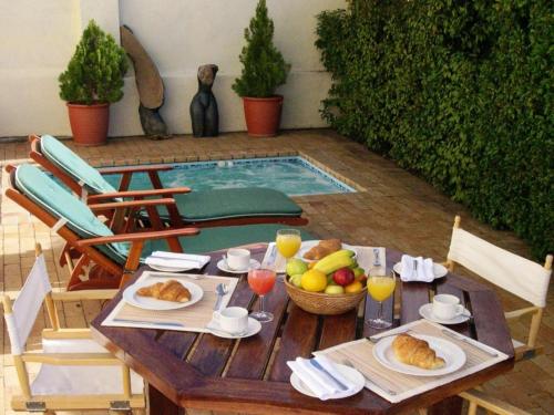 une table avec de la nourriture et des fruits dessus avec une piscine dans l'établissement Esperanza Guest House, au Cap