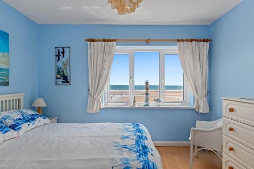 ein blaues Schlafzimmer mit einem Bett und einem Fenster mit Blick auf den Strand in der Unterkunft Strand Cottage - Direct Beach Access in Saundersfoot