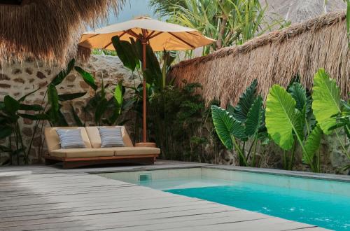 ein Sonnenschirm und Stühle neben einem Pool in der Unterkunft Boni Beach Lombok Boutique Hotel in Selong Belanak