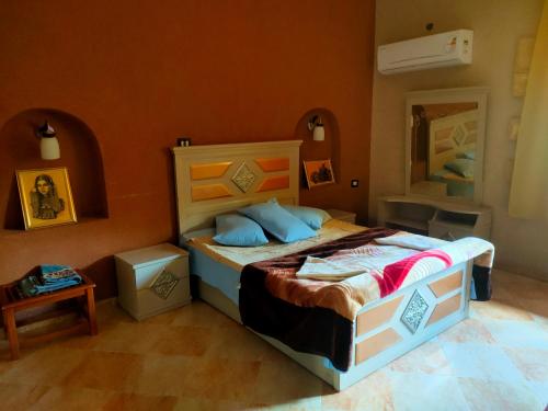 a bedroom with a bed with an orange wall at Panta Lodge Siwa بنتا لودج سيوة in Siwa