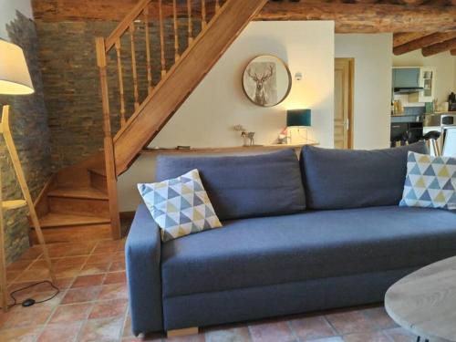 a blue couch in a living room with a staircase at La Louronnaise in Bordères-Louron